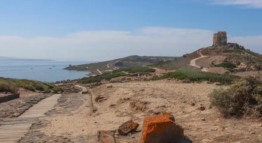 Torre aragonese su un colle roccioso, con rovine antiche e mare sullo sfondo, un paesaggio suggestivo di Tharros, Sardegna.