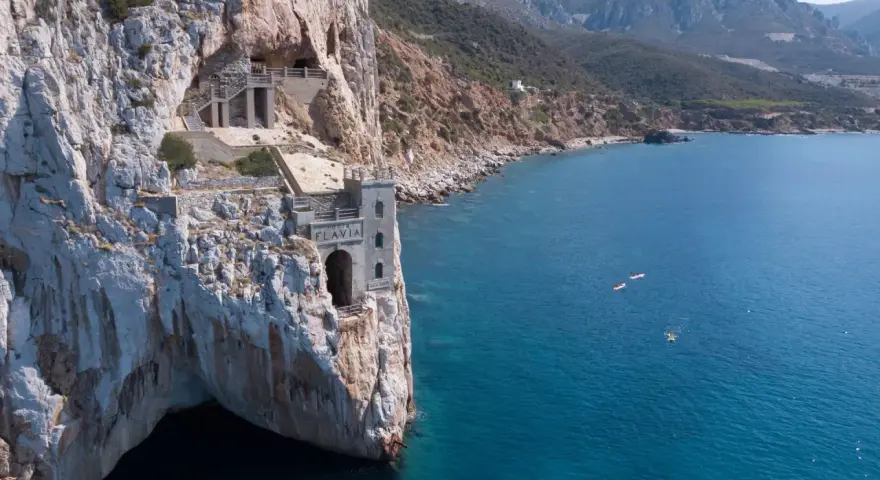 Porto Flavia, un'antica miniera a picco sul mare. Come arrivare: in auto o con tour in barca per ammirare la costa.