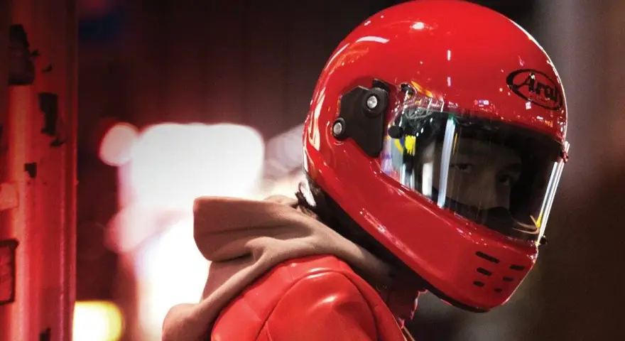 Un motociclista indossa un casco integrale rosso brillante, pronto per la strada.