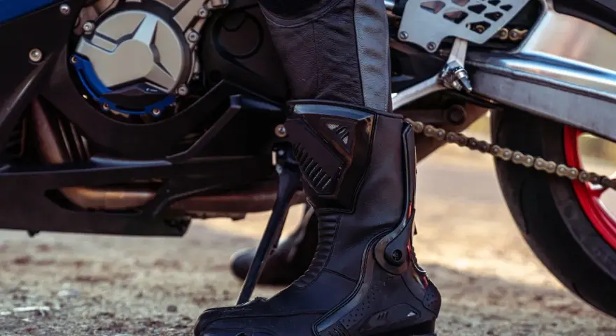 Stivale da motociclista in pelle nera, con protezioni rigide e suola robusta, pronto per l'avventura.