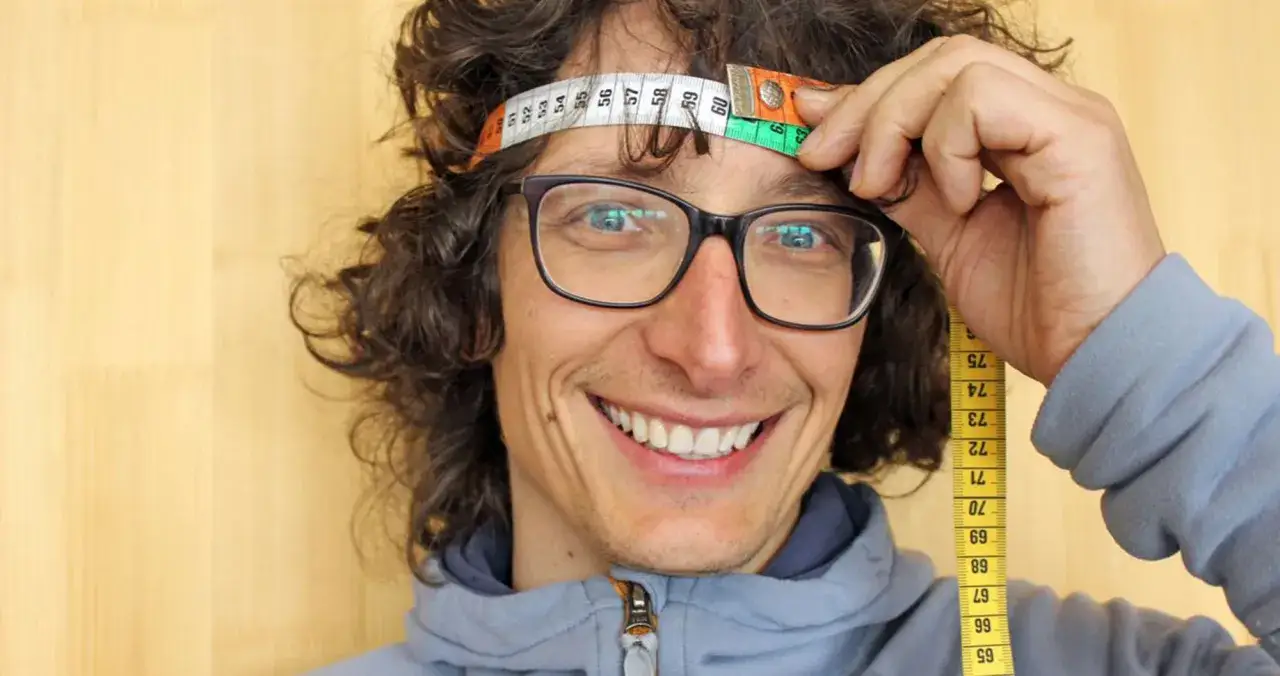 Uomo con occhiali misura la circonferenza della testa per le misure del casco LS2.