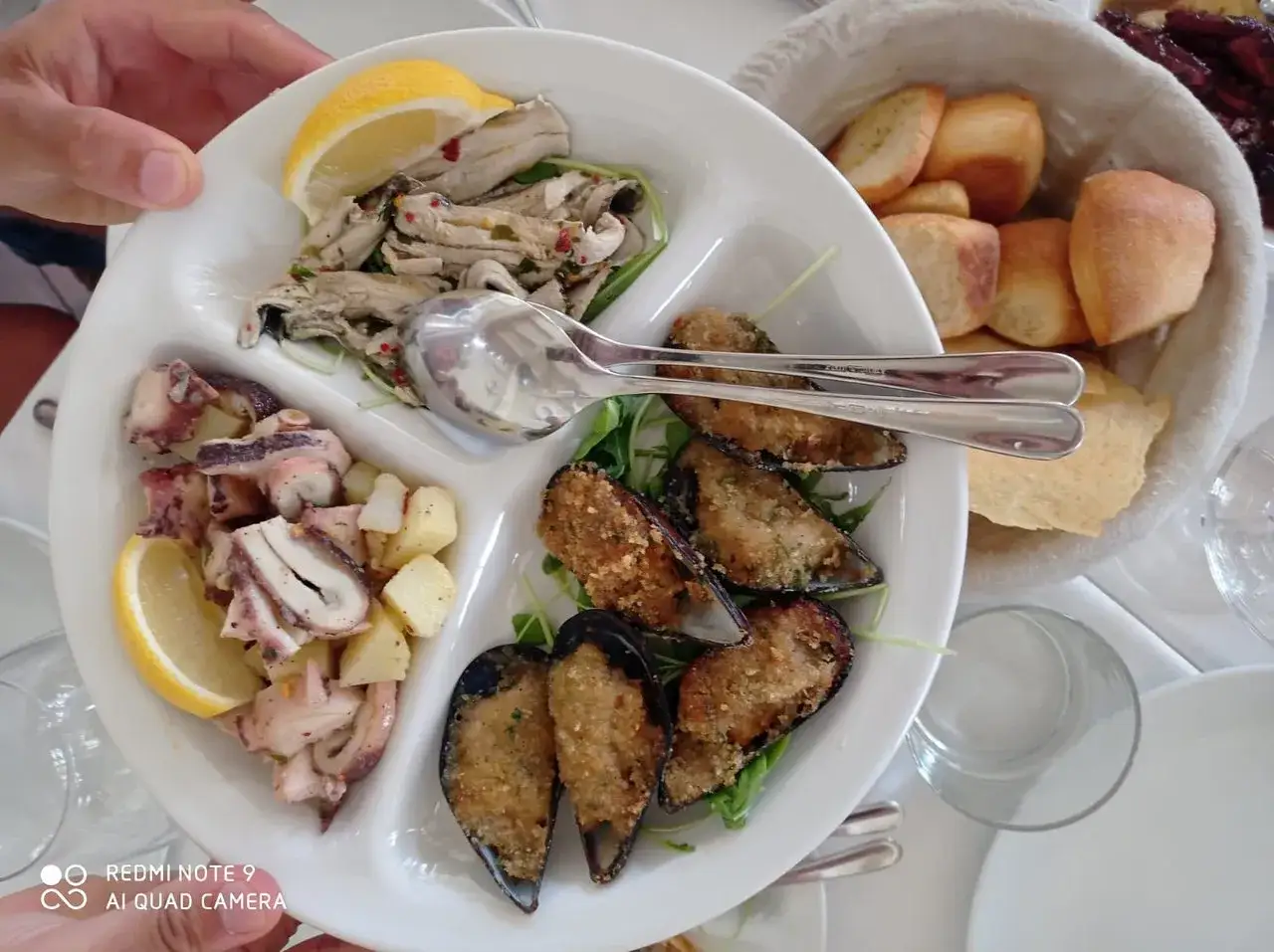 Antipasto di mare in un ristorante a Golfo Aranci: alici marinate, insalata di polpo e patate, cozze gratinate.