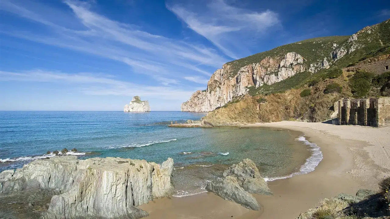La spiaggia di Masua, con il Pan di Zucchero in lontananza, incanta con le sue acque cristalline e le suggestive rovine industriali.
