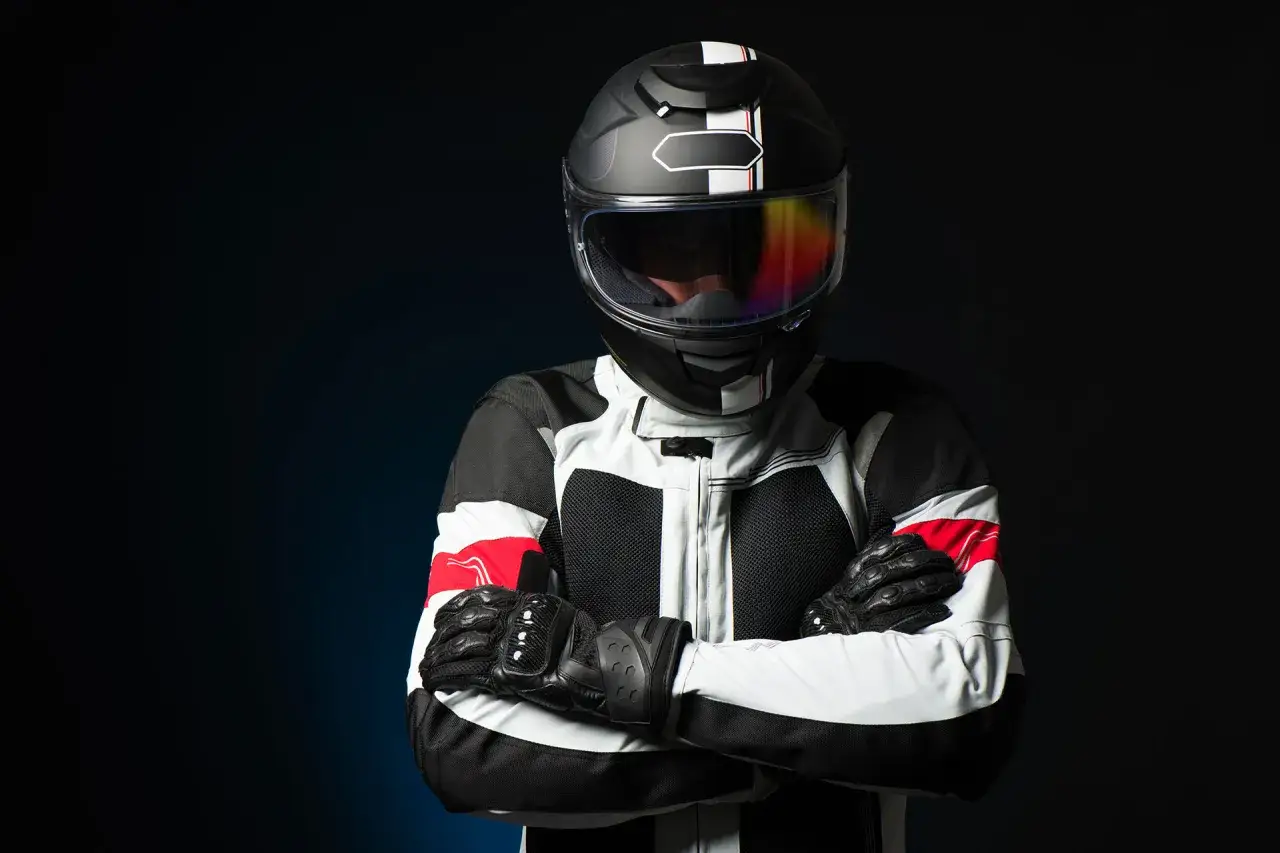 Motociclista con casco e giacca da corsa, guanti neri. Indossa le protezioni obbligatorie moto per la sicurezza.