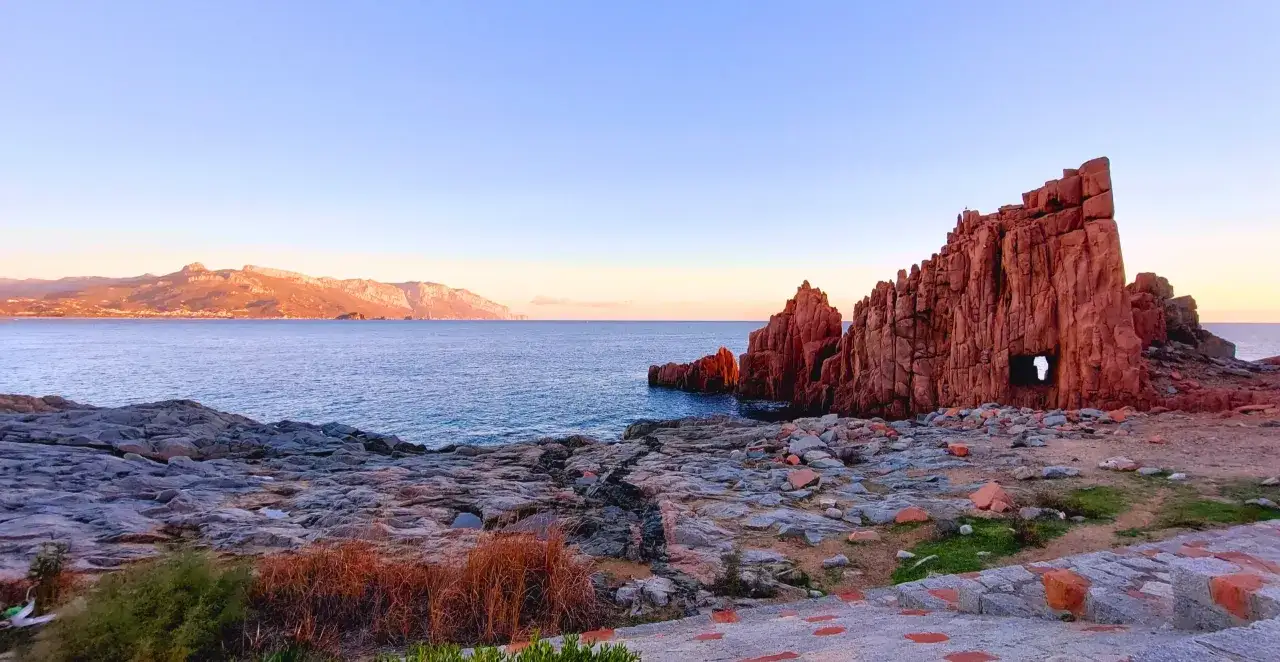 Le rocce rosse di Arbatax si ergono maestose sul mare blu, con un arco naturale scavato nella roccia.