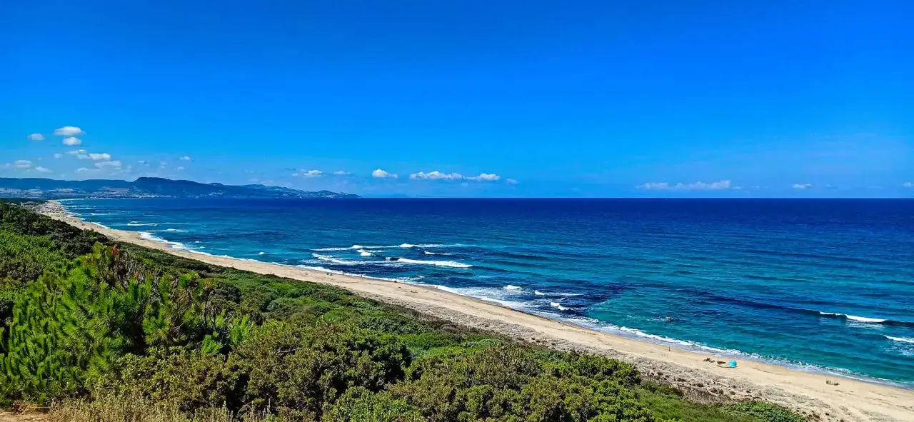 Spiaggia di Budoni con vegetazione mediterranea e mare cristallino. Un luogo ideale per scoprire cosa vedere a Budoni.