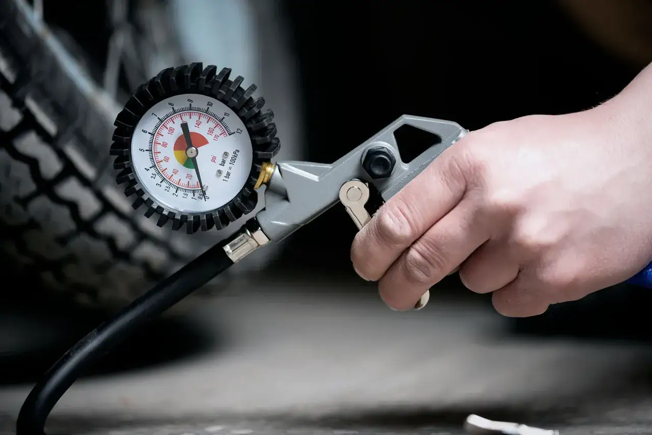Controllo della pressione gomme moto con manometro. La mano tiene lo strumento per verificare la corretta pressione.