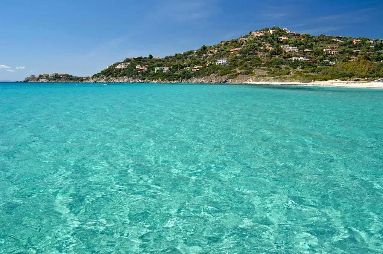 Acque cristalline e una collina verdeggiante punteggiata di case bianche caratterizzano la spiaggia Torre delle Stelle.