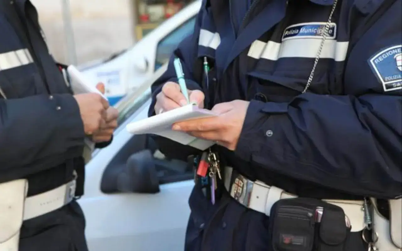 Agenti di polizia locale scrivono una multa, ricordando l'obbligo casco motorino per la sicurezza.