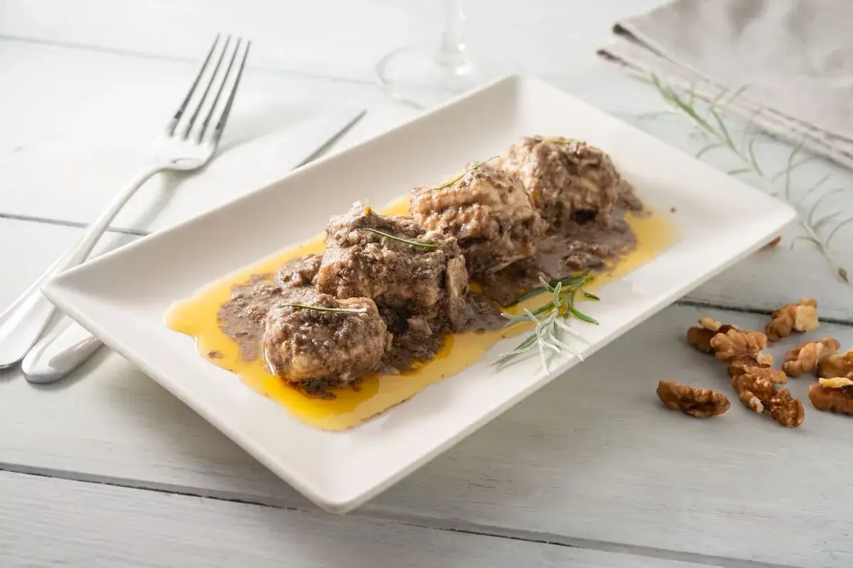 Burrida cagliaritana: gustosi bocconcini di pesce in salsa scura e olio dorato, guarniti con rosmarino.