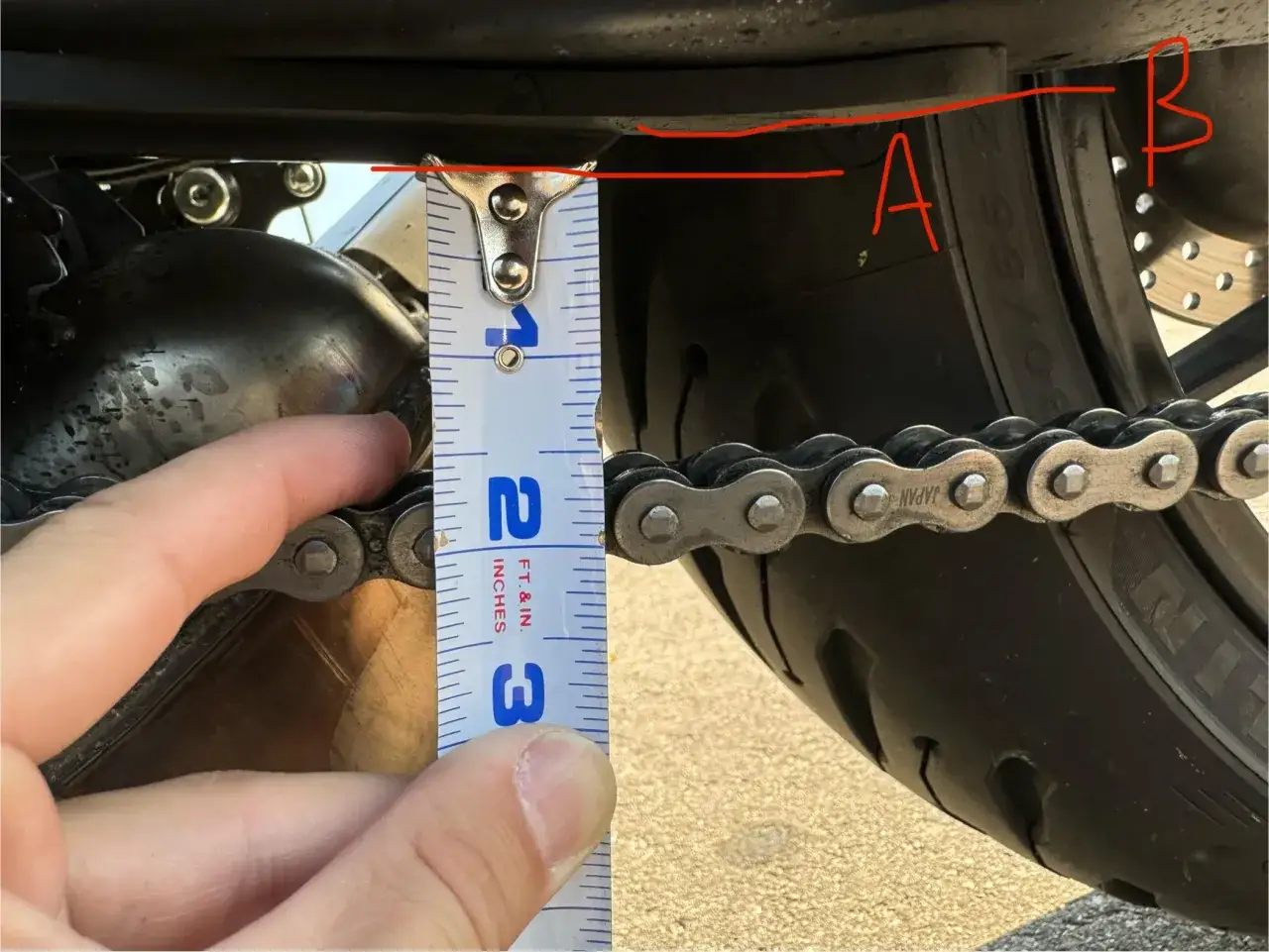 Misura la tensione della catena della moto con un righello. La catena &egrave; troppo allentata se si muove pi&ugrave; di 2-3 cm.