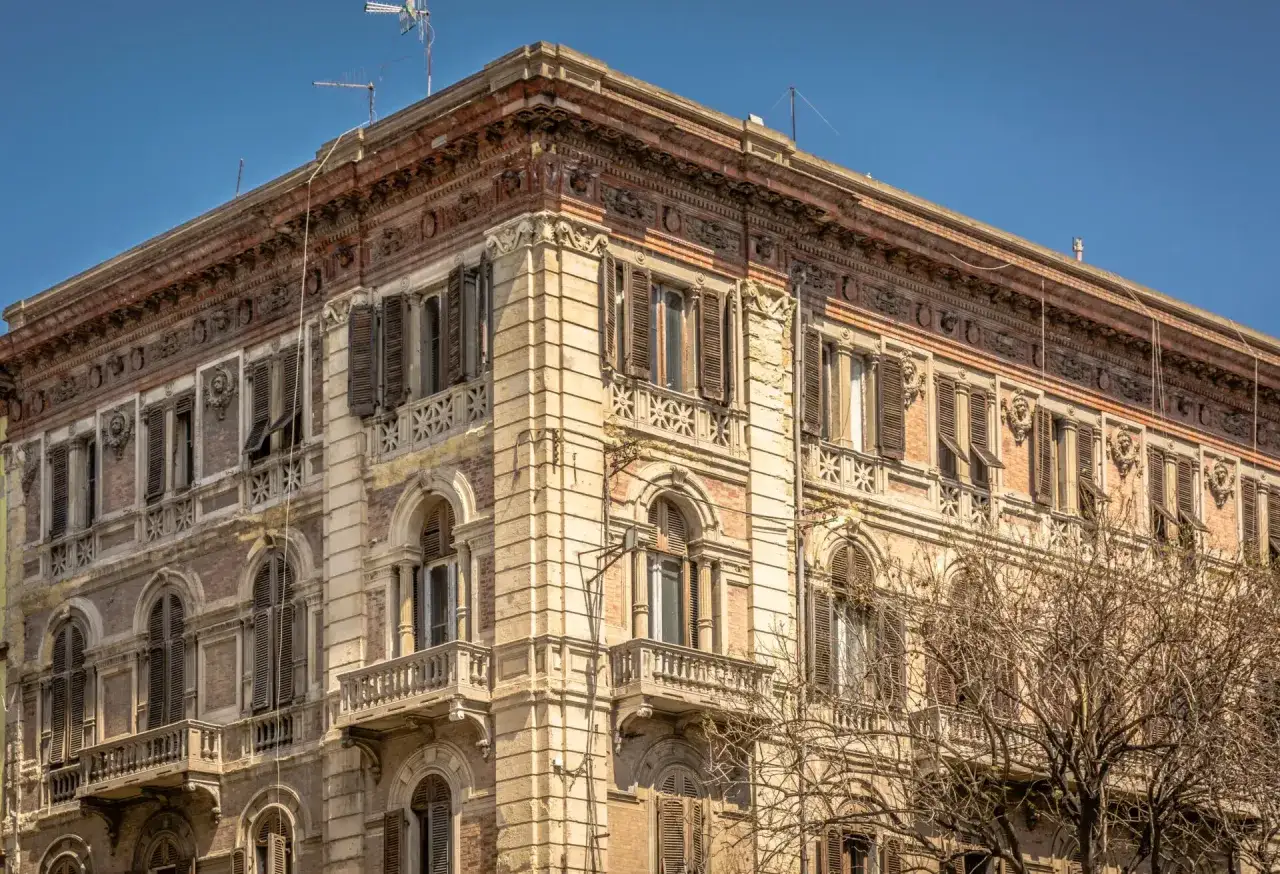 Angolo del Palazzo Accardo a Cagliari, con facciata in pietra chiara, balconi in ferro battuto e finestre con persiane.