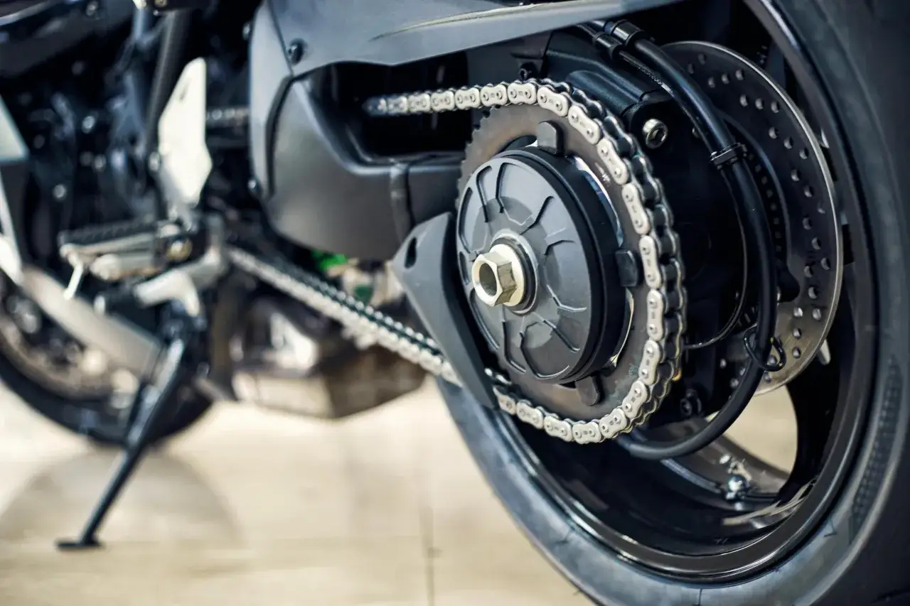 Dettaglio della sostituzione catena moto: la nuova catena cromata avvolta attorno alla corona posteriore e al pignone.