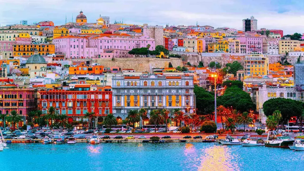 Colorate case affacciate sul porto nel quartiere Marina di Cagliari. Barche ormeggiate nell'acqua azzurra.