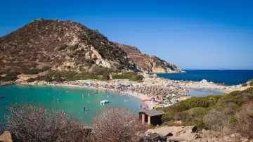 Una giornata di sole a Punta Molentis beach, con acque cristalline, sabbia dorata e tante persone che si godono il mare.