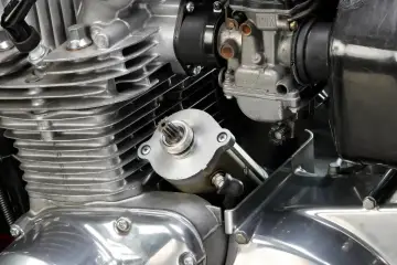 Dettaglio del motore di una moto: il test del motorino di avviamento è in primo piano, con il carburatore e le alette di raffreddamento visibili.