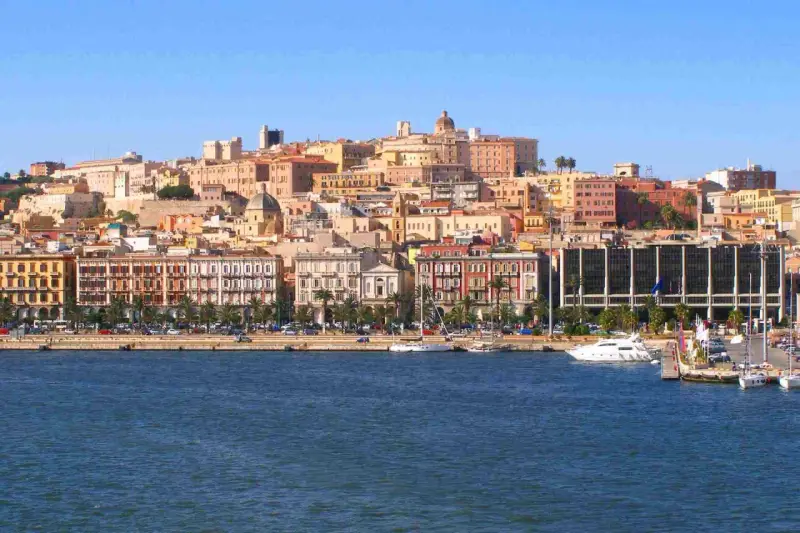 Vista del quartiere Marina di Cagliari con palazzi colorati, palme e yacht ormeggiati.